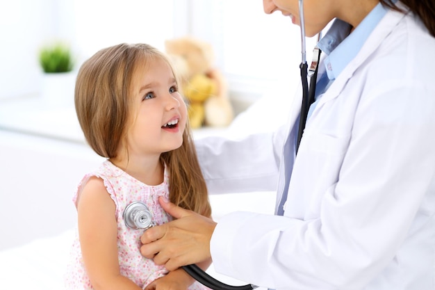 Doctor examinando a una niña con estetoscopio.