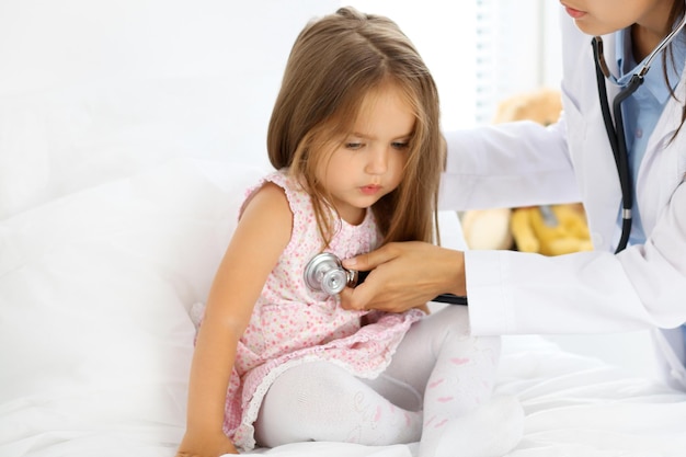 Doctor examinando a una niña con estetoscopio.