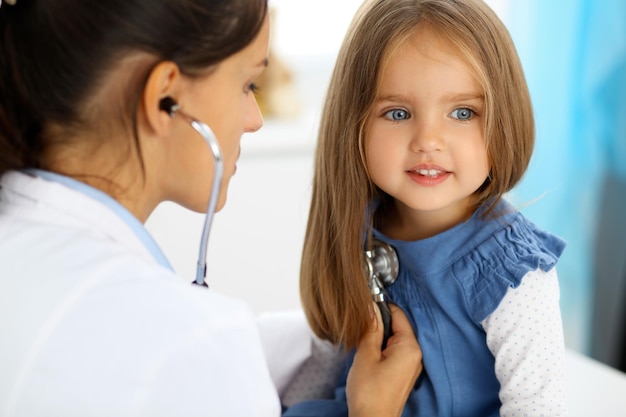 Doctor examinando a una niña con estetoscopio.