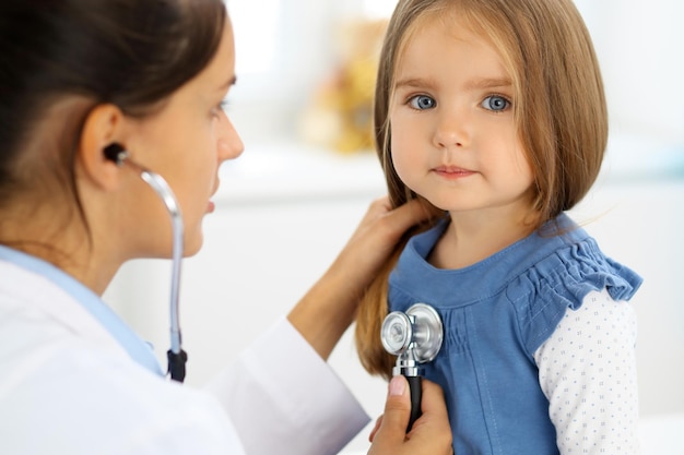 Doctor examinando a una niña con estetoscopio.