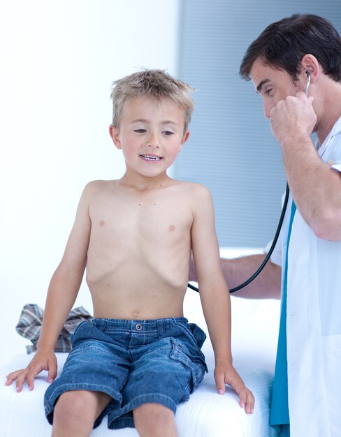 Doctor examinando a un niño pequeño con estetoscopio