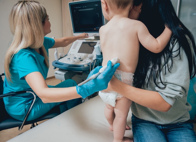 Doctor examinando a un niño pequeño retenido por su madre