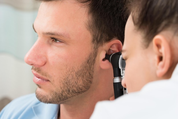 Doctor examinando el oído del hombre