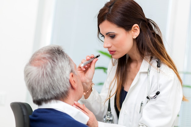 Doctor examinando los ojos del paciente masculino mayor