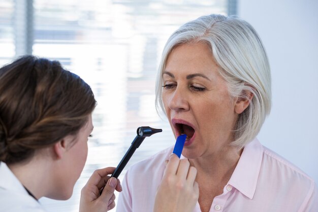 Doctor examinando pacientes dientes con otoscopio