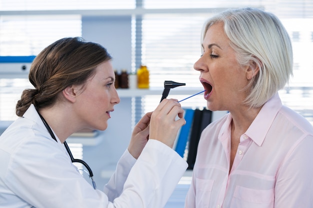 Doctor examinando pacientes dientes con otoscopio