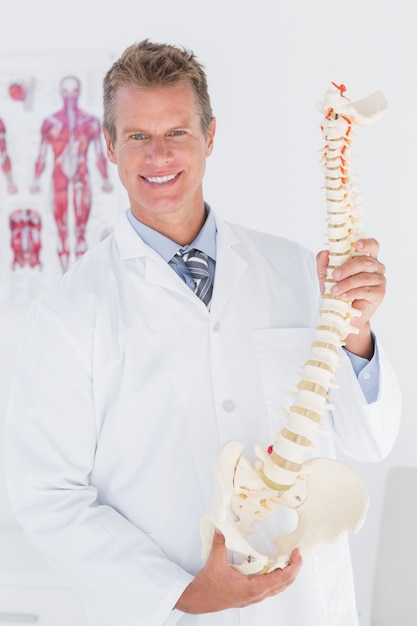 Doctor feliz mostrando la columna vertebral anatómica