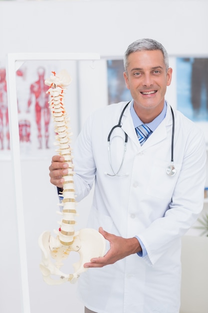 Doctor feliz mostrando la columna vertebral anatómica