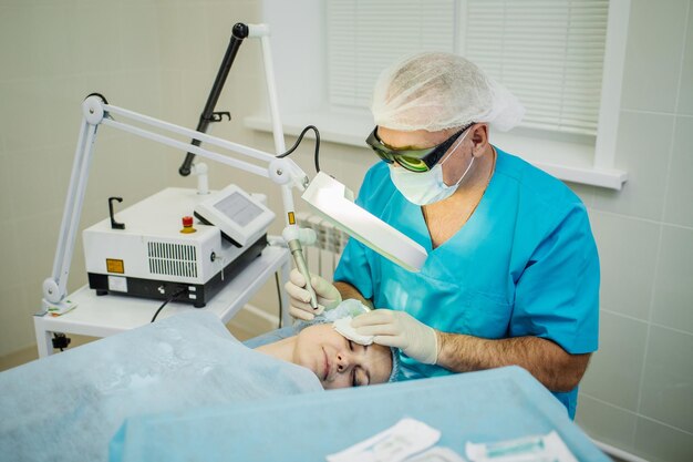 Doctor en gafas de seguridad con láser para tratamiento facial en clínica de cosmetología