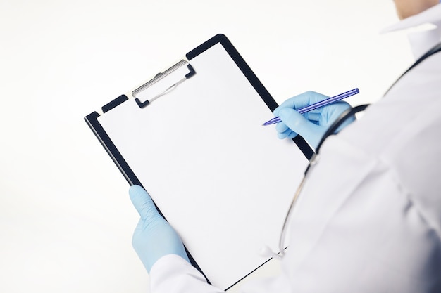 Foto doctor en guantes azules sosteniendo portapapeles médico con hoja de papel en blanco vacía aislado en blanco