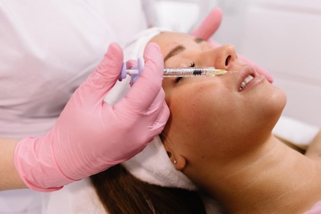 Doctor en guantes dando inyecciones de botox mujer en labios