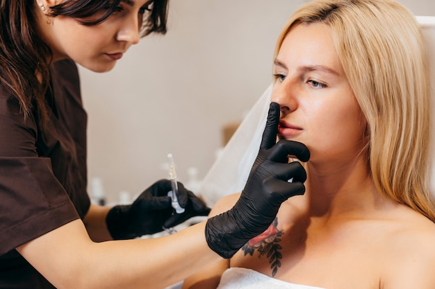 Doctor en guantes dando inyecciones de mujer en labios