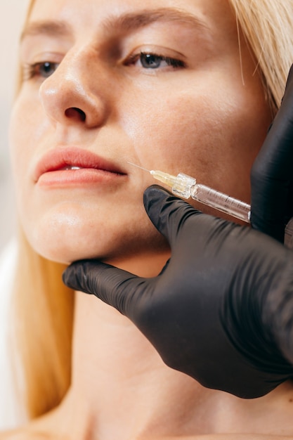 Doctor en guantes dando inyecciones de mujer en labios