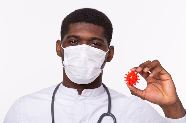 Doctor con guantes estériles sosteniendo una maqueta del virus COVID-19