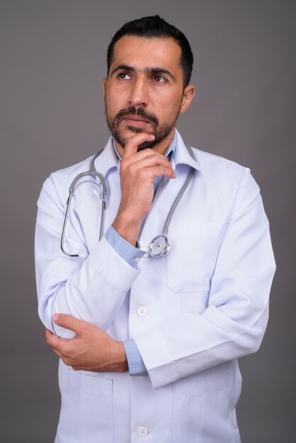 Doctor guapo con barba contra la pared gris