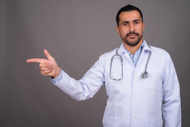 Doctor guapo con barba contra la pared gris