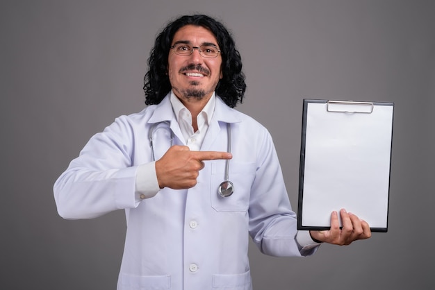 Foto doctor guapo con bigote contra la pared gris