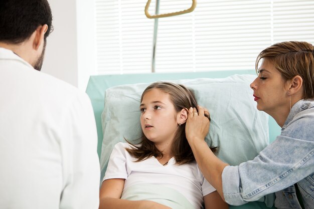 Doctor hablando con niña paciente en la habitación del hospital