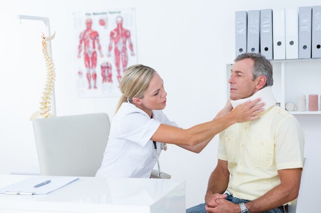 Doctor hablando con paciente usando cuello ortopédico