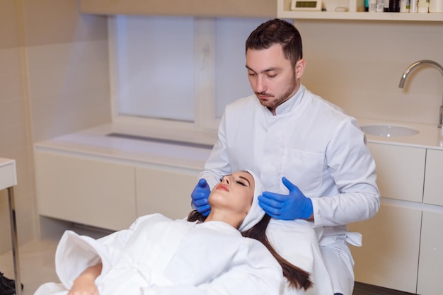 El doctor hace una marca en el rostro de una hermosa mujer antes del procedimiento del cometa para corregir la forma del rostro.