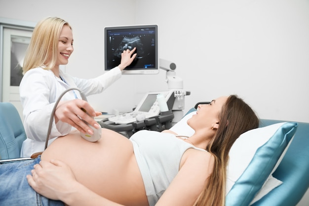 Doctor haciendo examen de ultrasonido del abdomen de la mujer embarazada.