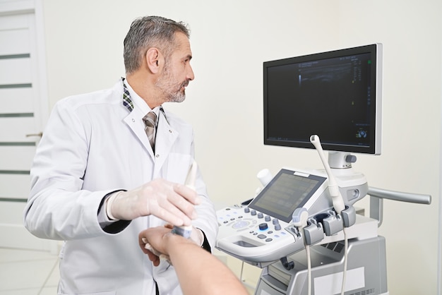 Doctor haciendo un examen de ultrasonido de la muñeca del patinet.