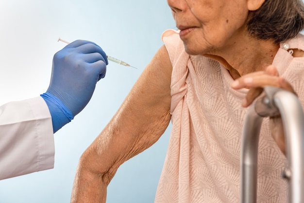 Doctor haciendo la inyección de la vacuna a la mujer mayor.