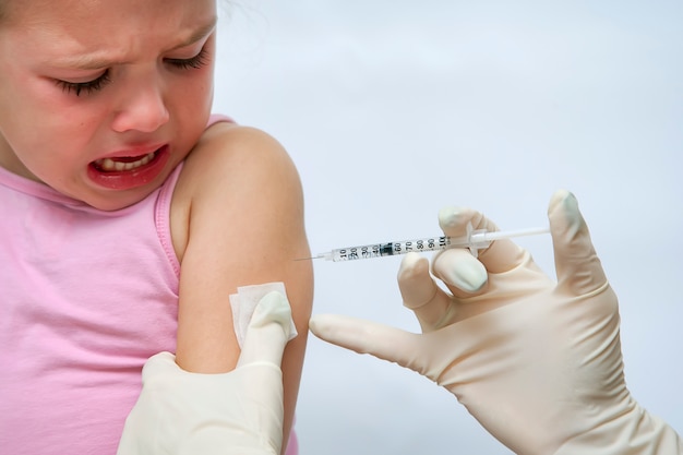 Doctor haciendo inyección de vacuna a niña llorando