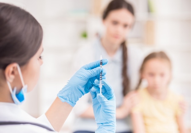 Doctor haciendo inyección de vacuna a la niña rubia.