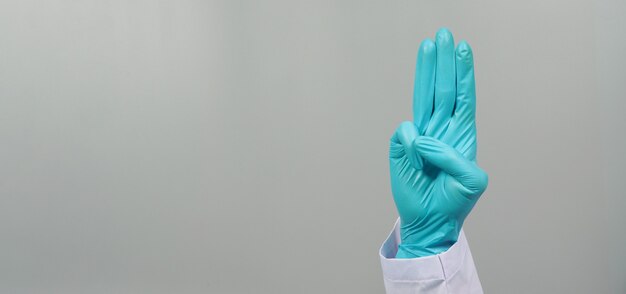 Doctor Hand tragen Latexhandschuh. Ein Handzeichen von 3 Fingern zeigt nach oben, was drei, dritte oder Proteste bedeutet.