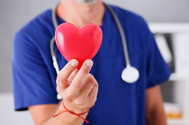 Foto doctor hombre espera en brazos corazón rojo