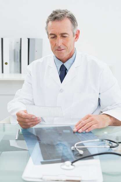 Doctor hombre leyendo una nota en el escritorio en la oficina