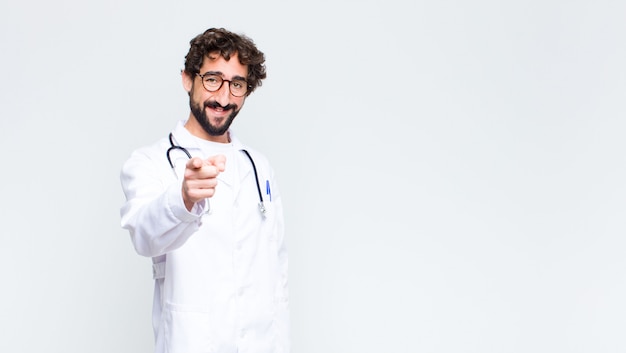 doctor hombre señalando con una sonrisa satisfecha, segura y amigable, eligiéndote