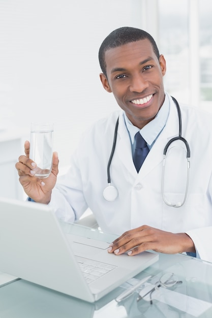 Doctor hombre sosteniendo un vaso de agua en consultorio médico