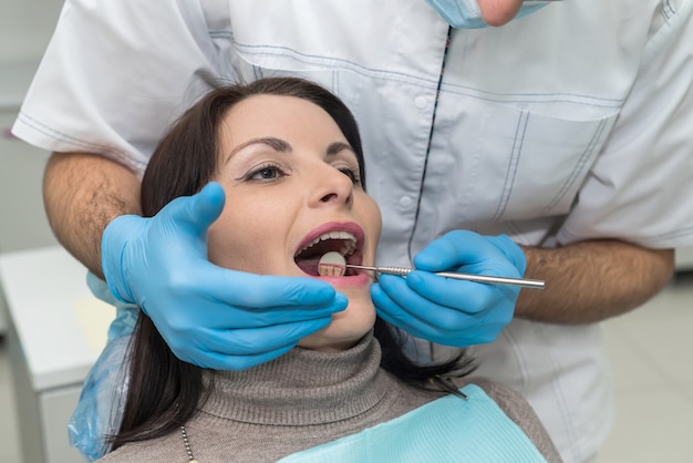 Doctor inspeccionando los dientes del paciente con espejo de cerca