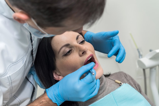 Doctor inspeccionando los dientes del paciente con espejo de cerca