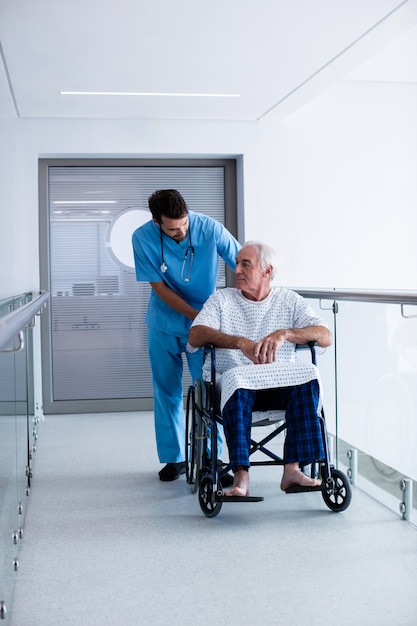 Doctor interactuando con un paciente masculino mayor en una silla de ruedas