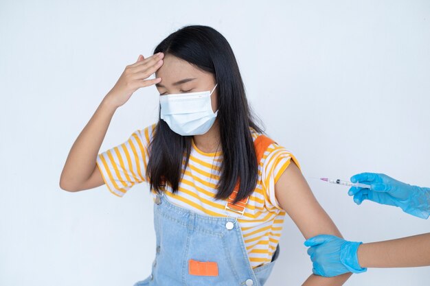 Doctor inyectando la vacunación en el brazo de la joven asiática sobre fondo blanco estudiante concepto médico