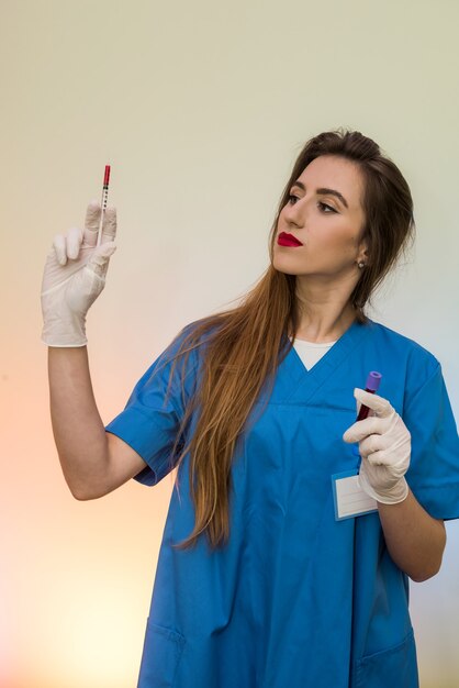 Foto doctor con jeringa y tubo de ensayo rojo posando en el hospital
