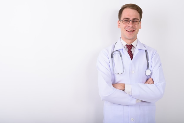 Doctor joven guapo con anteojos en la pared blanca