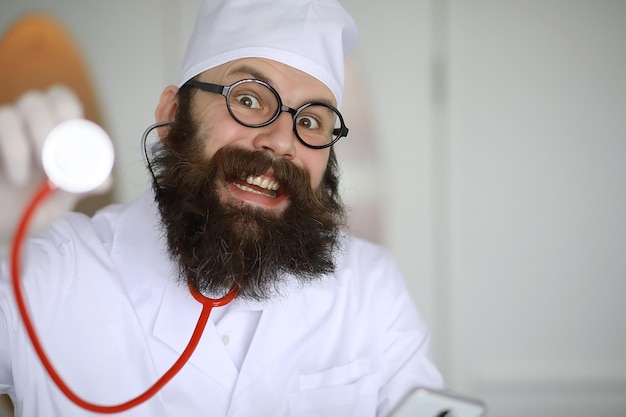 Doctor loco. Un científico loco con barba realiza experimentos en un laboratorio científico. Realiza investigaciones utilizando una jeringa y un estetoscopio.