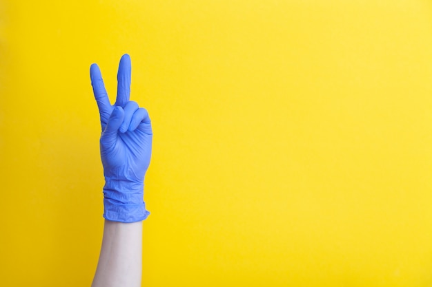 Doctor mano en guantes médicos de látex lila mostrando dos dedos