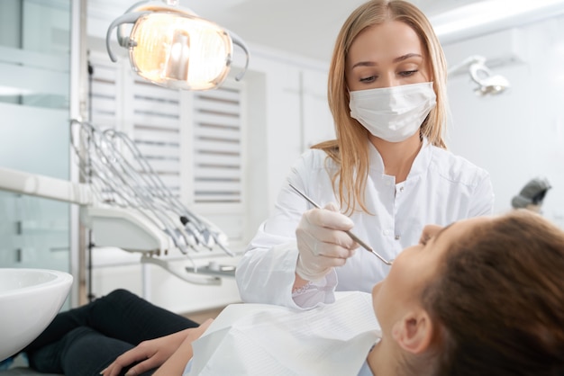 Foto doctor en máscara médica que trata los dientes del paciente.