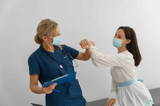 Doctor con máscara protectora contra el codazo codicioso tocando al saludar al paciente