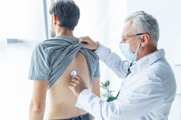 Foto doctor en máscara que examina al paciente