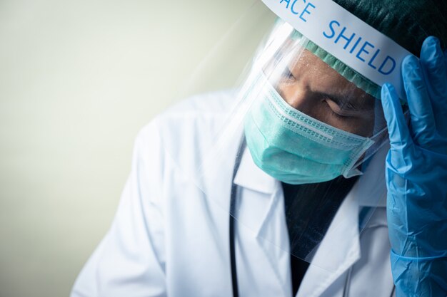 Doctor masculino asiático vistiendo careta y uniforme con estetoscopio