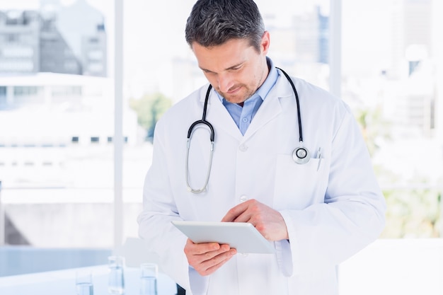 Doctor masculino concentrado que usa la tableta digital