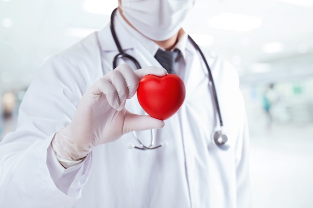 Foto doctor masculino con forma de corazón rojo. para alentar a los médicos a alentar al personal médico a superar el concepto médico y de atención médica covid-19.