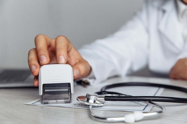 Doctor masculino en la oficina está sellando el documento médico