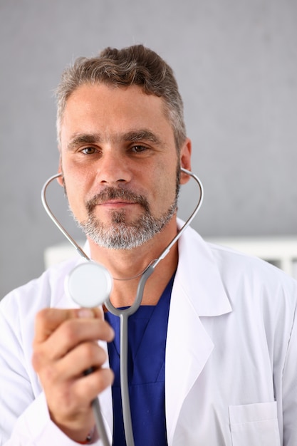 Doctor masculino sostenga en la cabeza del estetoscopio del brazo en frente